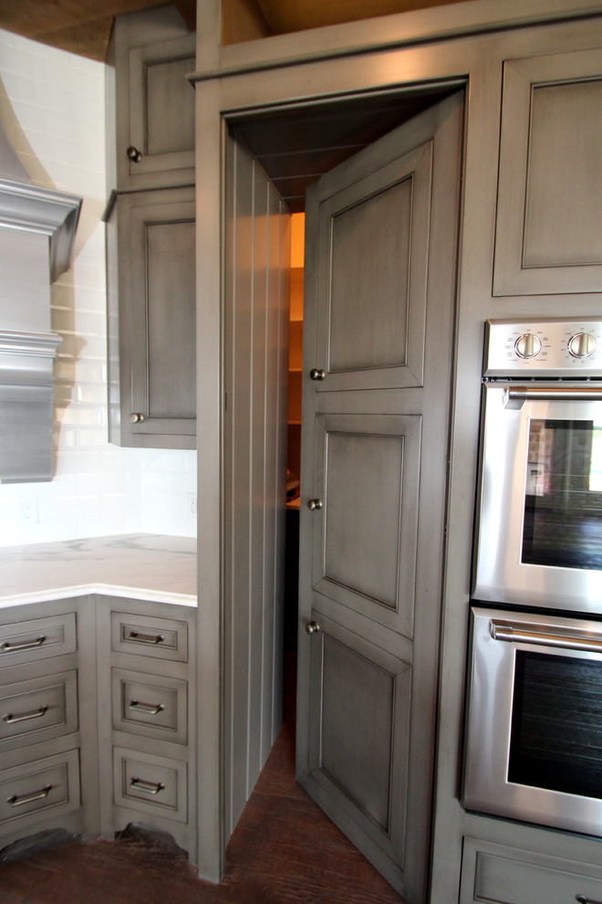 Bild på ett medelhavsstil kök, med en undermonterad diskho, luckor med infälld panel, grå skåp, marmorbänkskiva, vitt stänkskydd, stänkskydd i porslinskakel, rostfria vitvaror, ljust trägolv och en köksö