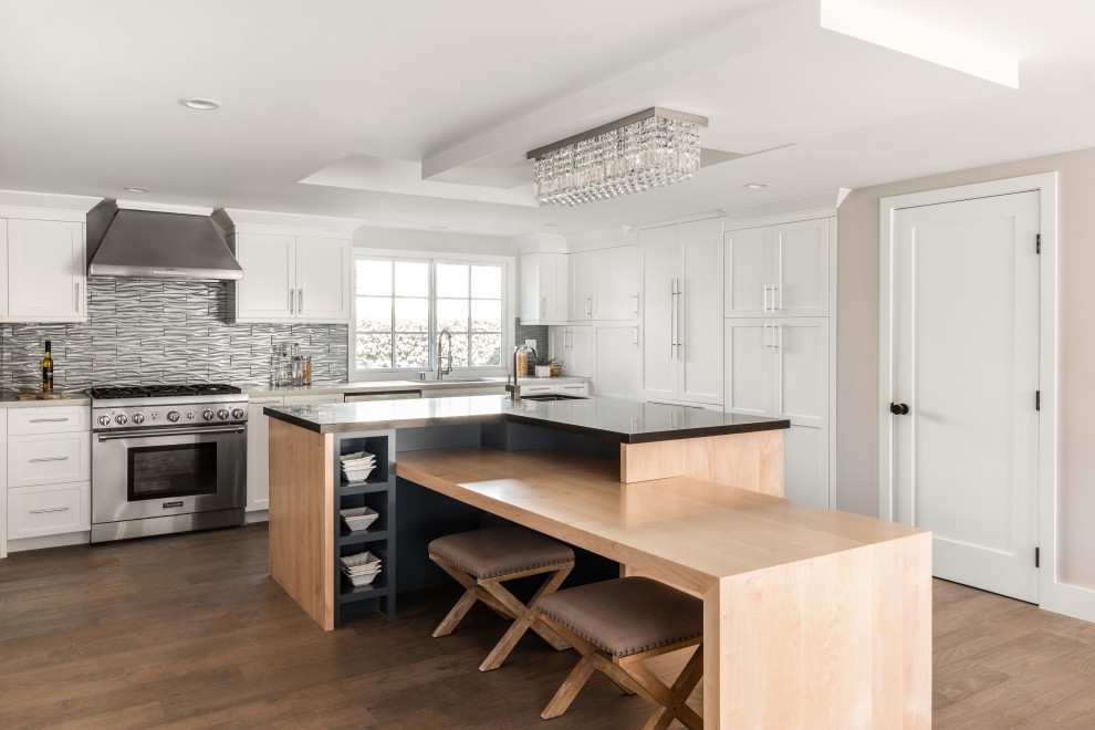Example of a large transitional l-shaped brown floor kitchen design in Los Angeles with an undermount sink, shaker cabinets, white cabinets, gray backsplash, stainless steel appliances, an island and brown countertops