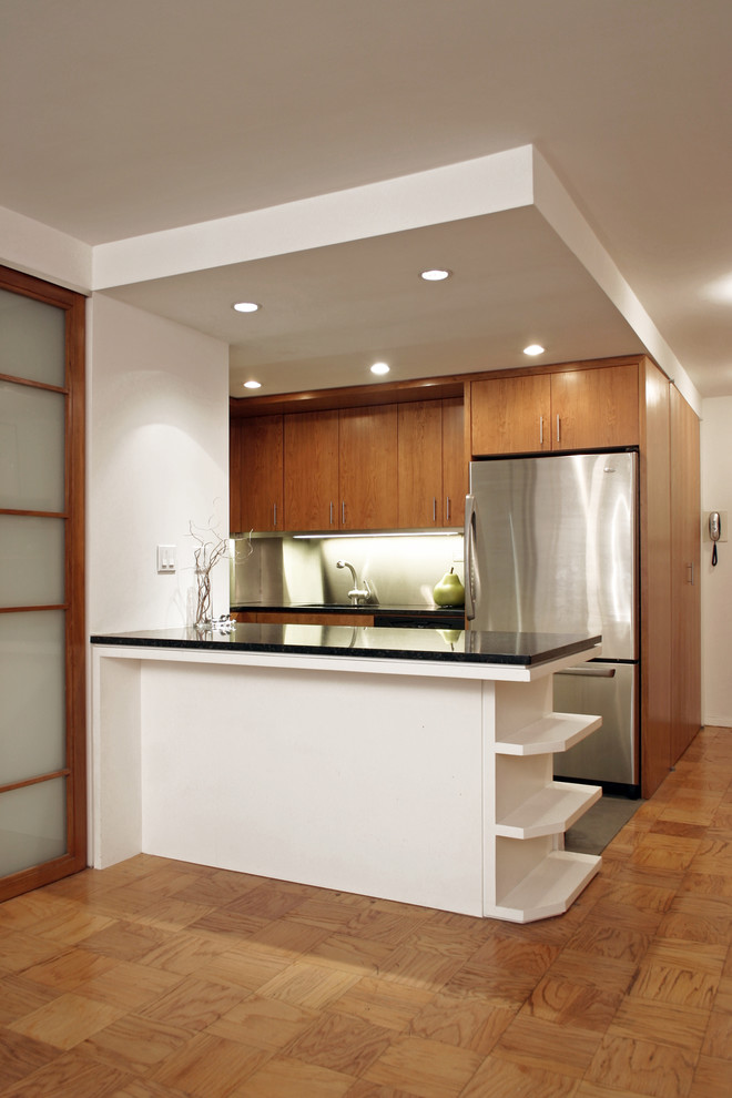 Inspiration for a mid-sized modern galley medium tone wood floor open concept kitchen remodel in New York with a drop-in sink, flat-panel cabinets, medium tone wood cabinets, granite countertops, stainless steel appliances and a peninsula