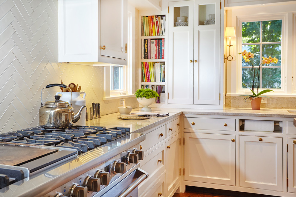 Photo of a farmhouse kitchen in New York with a submerged sink, beaded cabinets, white cabinets, marble worktops, white splashback, ceramic splashback, integrated appliances, light hardwood flooring and an island.