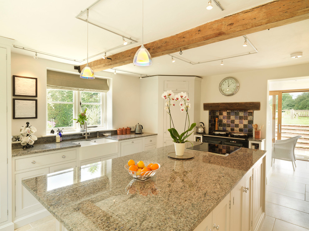Inspiration for a medium sized rural u-shaped open plan kitchen in Hampshire with a belfast sink, beaded cabinets, grey cabinets, granite worktops, multi-coloured splashback, glass tiled splashback, stainless steel appliances, limestone flooring and an island.