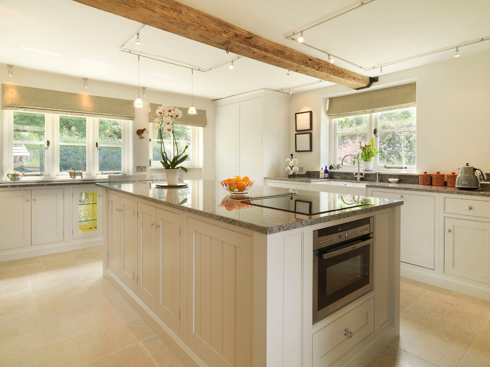 Foto på ett mellanstort lantligt kök, med en rustik diskho, luckor med profilerade fronter, grå skåp, granitbänkskiva, flerfärgad stänkskydd, stänkskydd i glaskakel, rostfria vitvaror, en köksö och kalkstensgolv