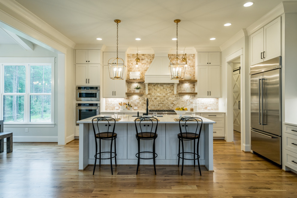 Inspiration for a large farmhouse l-shaped medium tone wood floor and brown floor kitchen remodel in Raleigh with a farmhouse sink, brick backsplash and stainless steel appliances