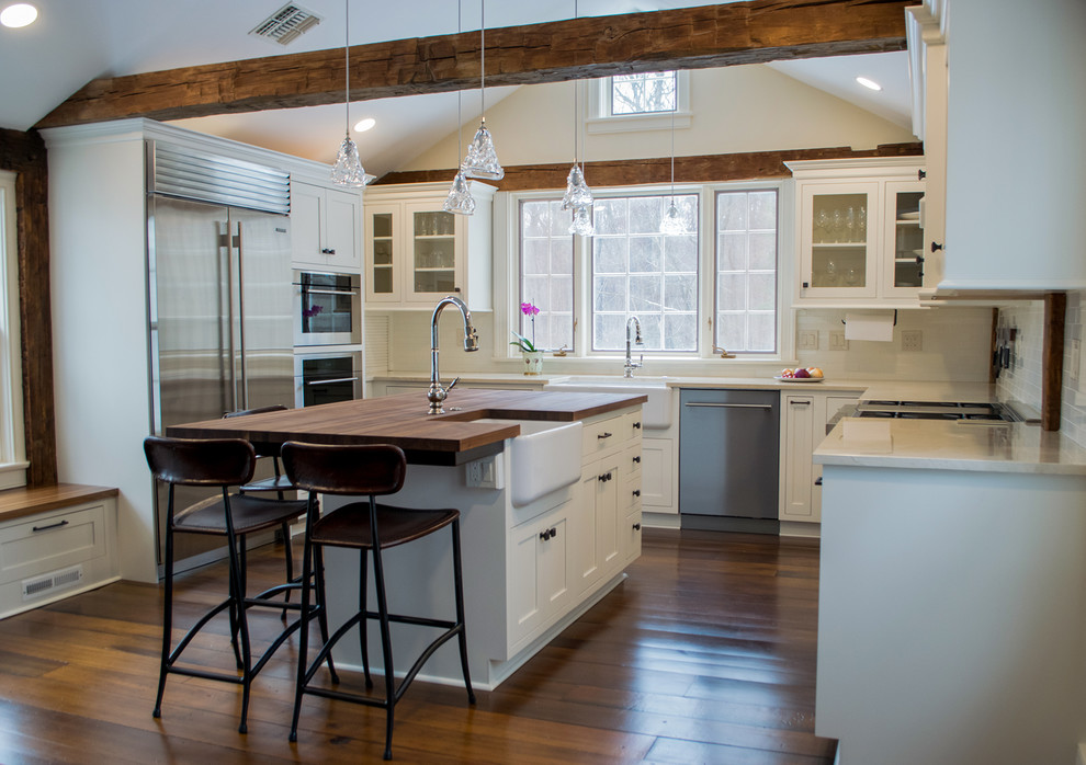 Idéer för ett mellanstort lantligt vit kök, med en rustik diskho, luckor med infälld panel, vita skåp, träbänkskiva, vitt stänkskydd, stänkskydd i tunnelbanekakel, rostfria vitvaror, mellanmörkt trägolv, en köksö och brunt golv