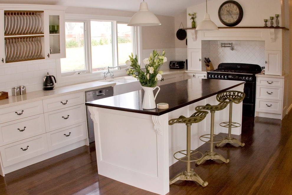Ejemplo de cocina ecléctica con puertas de armario blancas, encimera de madera, salpicadero blanco, una isla y salpicadero de azulejos de cerámica