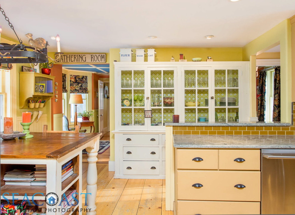 Inspiration for a mid-sized cottage u-shaped medium tone wood floor enclosed kitchen remodel in Other with a farmhouse sink, beige cabinets, granite countertops, beige backsplash, glass tile backsplash and stainless steel appliances