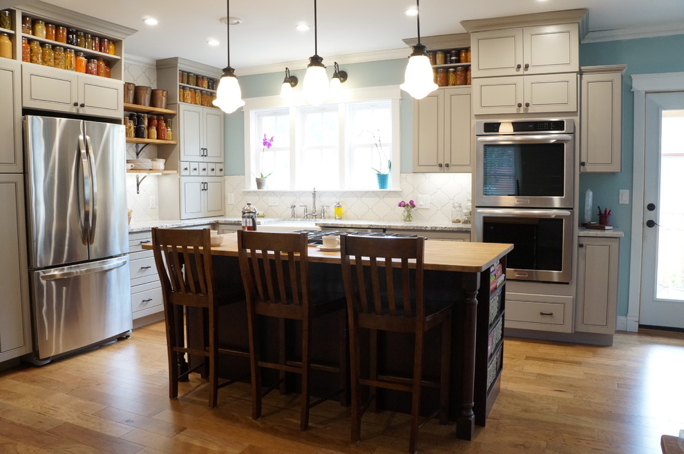 Eat-in kitchen - mid-sized country l-shaped light wood floor and brown floor eat-in kitchen idea in Denver with a farmhouse sink, beaded inset cabinets, gray cabinets, wood countertops, white backsplash, porcelain backsplash, stainless steel appliances and an island