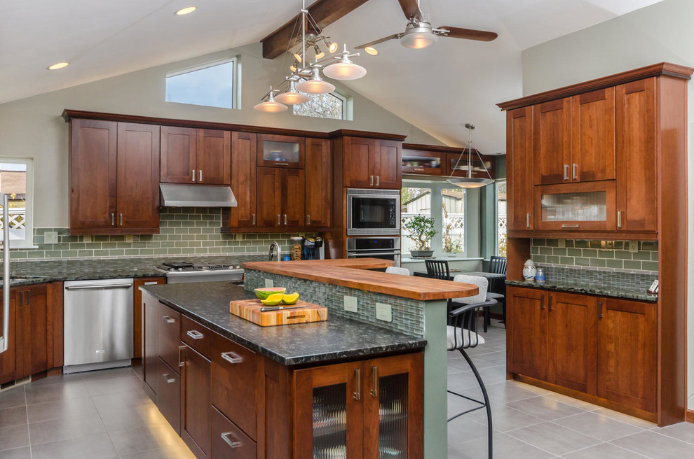 Cette photo montre une grande cuisine américaine chic en U et bois brun avec un placard à porte shaker, une crédence verte, un électroménager en acier inoxydable, un évier 1 bac, un plan de travail en granite, une crédence en mosaïque, un sol en carrelage de porcelaine, îlot, un sol gris et un plan de travail gris.