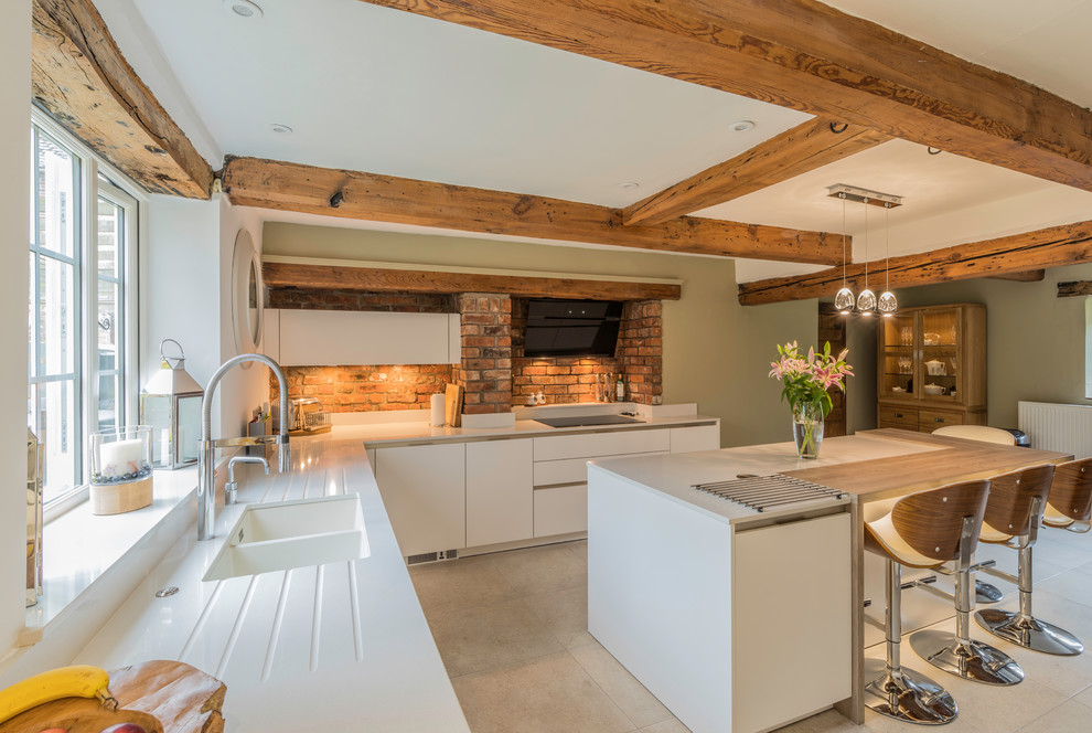 This is an example of a country kitchen in Cheshire with flat-panel cabinets, white cabinets and a breakfast bar.