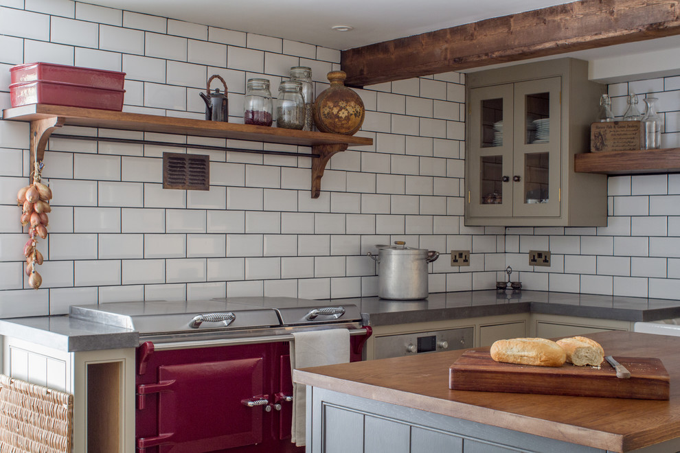 Idéer för ett avskilt, litet lantligt l-kök, med en rustik diskho, grå skåp, vitt stänkskydd, stänkskydd i tunnelbanekakel, en köksö, luckor med profilerade fronter och färgglada vitvaror