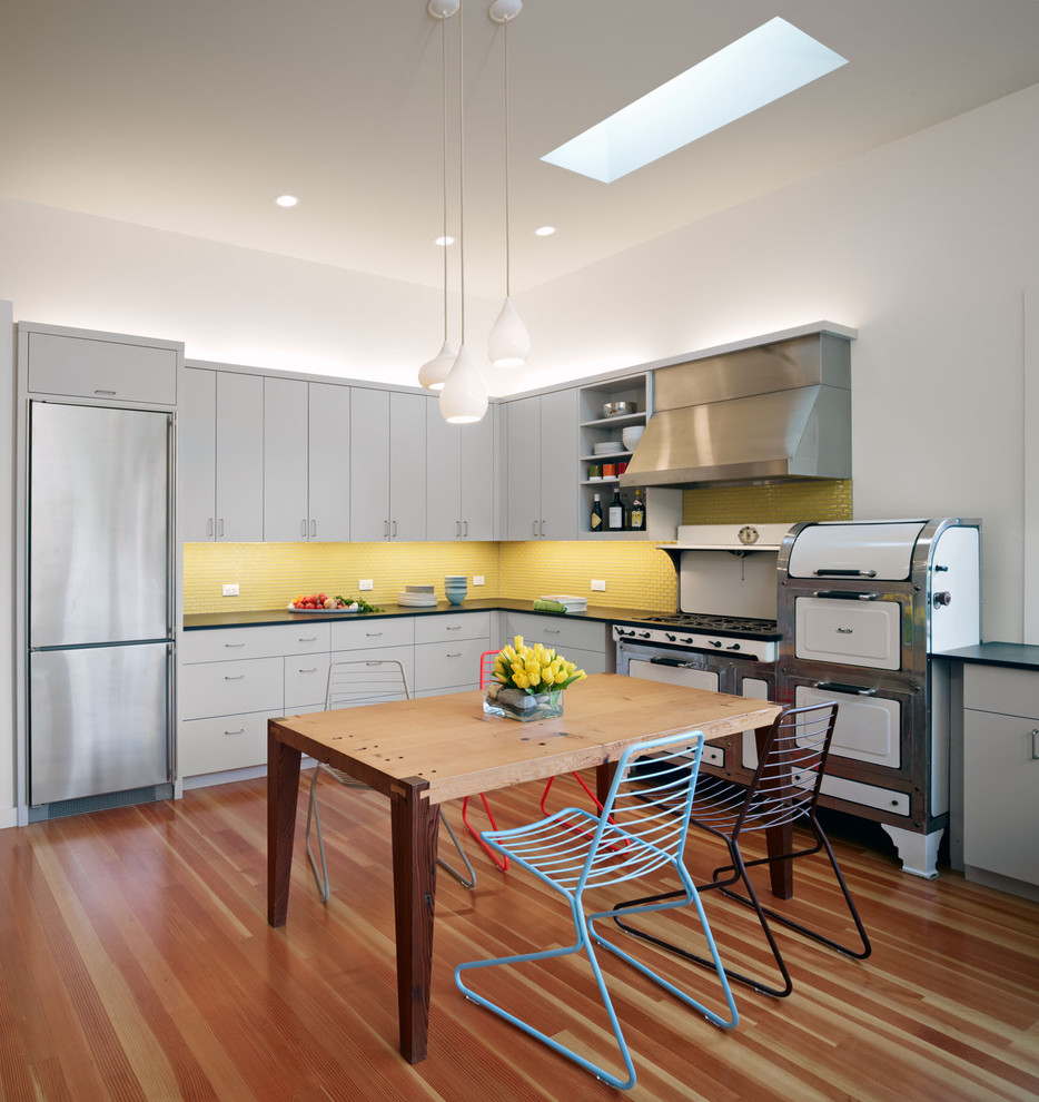 Example of a large trendy u-shaped eat-in kitchen design in San Francisco with white appliances, yellow backsplash, flat-panel cabinets, gray cabinets, mosaic tile backsplash, an undermount sink and no island