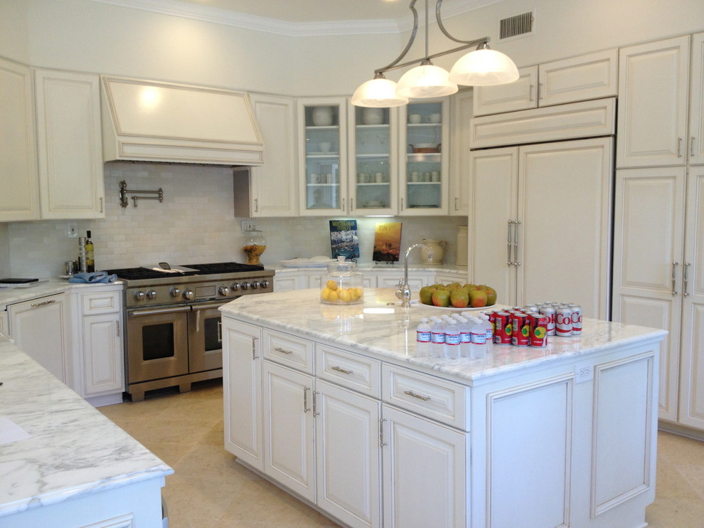 Photo of a medium sized traditional u-shaped kitchen in Los Angeles with an island, raised-panel cabinets, distressed cabinets, marble worktops, white splashback, ceramic splashback, stainless steel appliances, a belfast sink and porcelain flooring.