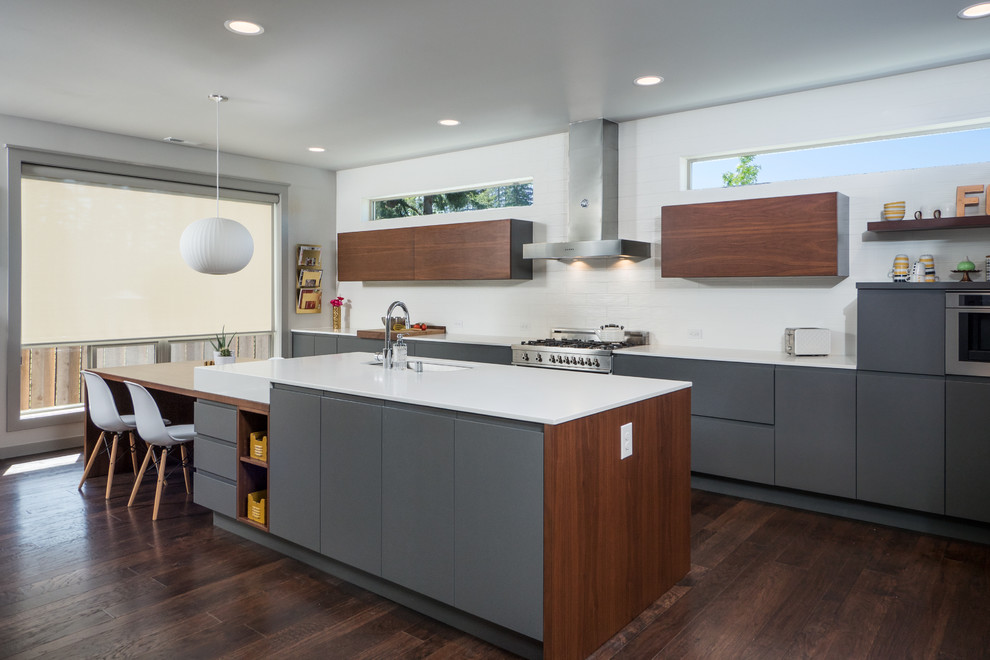 Trendy dark wood floor open concept kitchen photo in Seattle with flat-panel cabinets, white backsplash, stainless steel appliances and an island