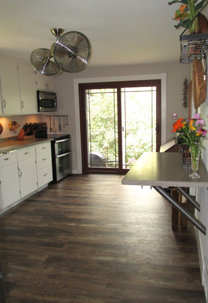 Foto di una cucina parallela country chiusa e di medie dimensioni con lavello integrato, ante bianche, elettrodomestici in acciaio inossidabile e nessuna isola