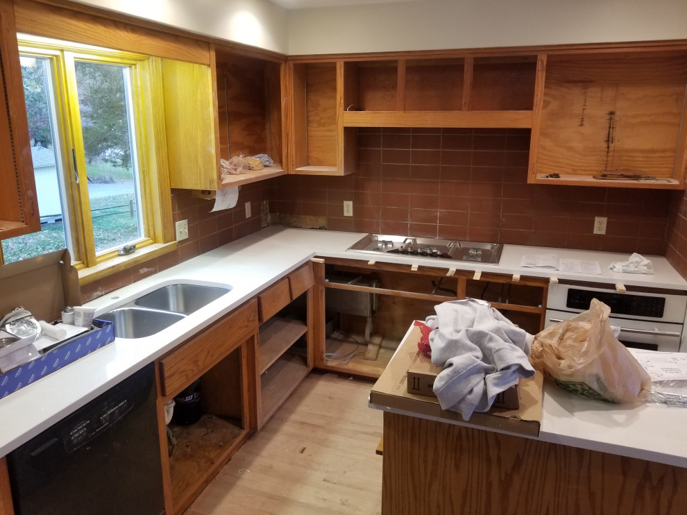 Example of a large farmhouse l-shaped light wood floor and brown floor eat-in kitchen design in Kansas City with an undermount sink, shaker cabinets, light wood cabinets, granite countertops, red backsplash, terra-cotta backsplash, stainless steel appliances, an island and white countertops