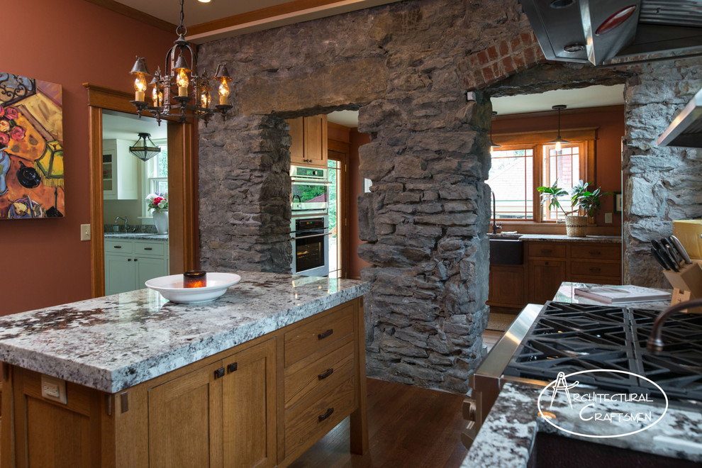 Photo of a rustic kitchen in Kansas City with a belfast sink, shaker cabinets, medium wood cabinets, granite worktops and integrated appliances.