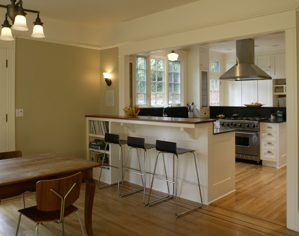 Example of a mid-sized classic u-shaped light wood floor eat-in kitchen design in Portland with shaker cabinets, white cabinets, granite countertops, stainless steel appliances and a peninsula