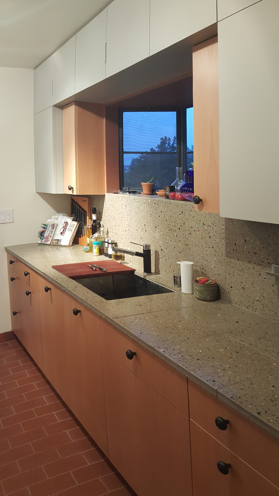 This is an example of a medium sized classic galley kitchen in Los Angeles with a submerged sink, flat-panel cabinets, medium wood cabinets, terrazzo worktops, grey splashback, integrated appliances and terracotta flooring.