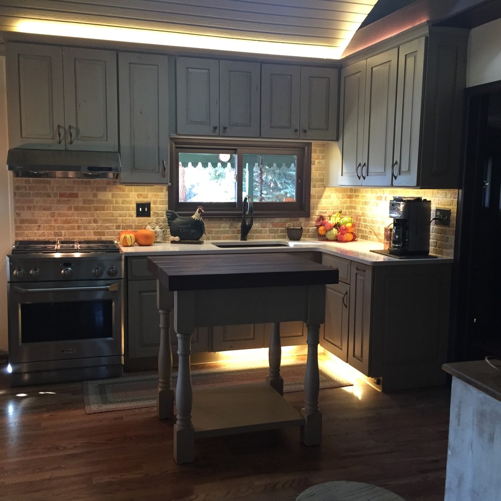 Foto på ett litet rustikt kök, med en undermonterad diskho, luckor med upphöjd panel, skåp i slitet trä, rostfria vitvaror, ljust trägolv, en köksö, bänkskiva i koppar, beige stänkskydd och stänkskydd i stenkakel