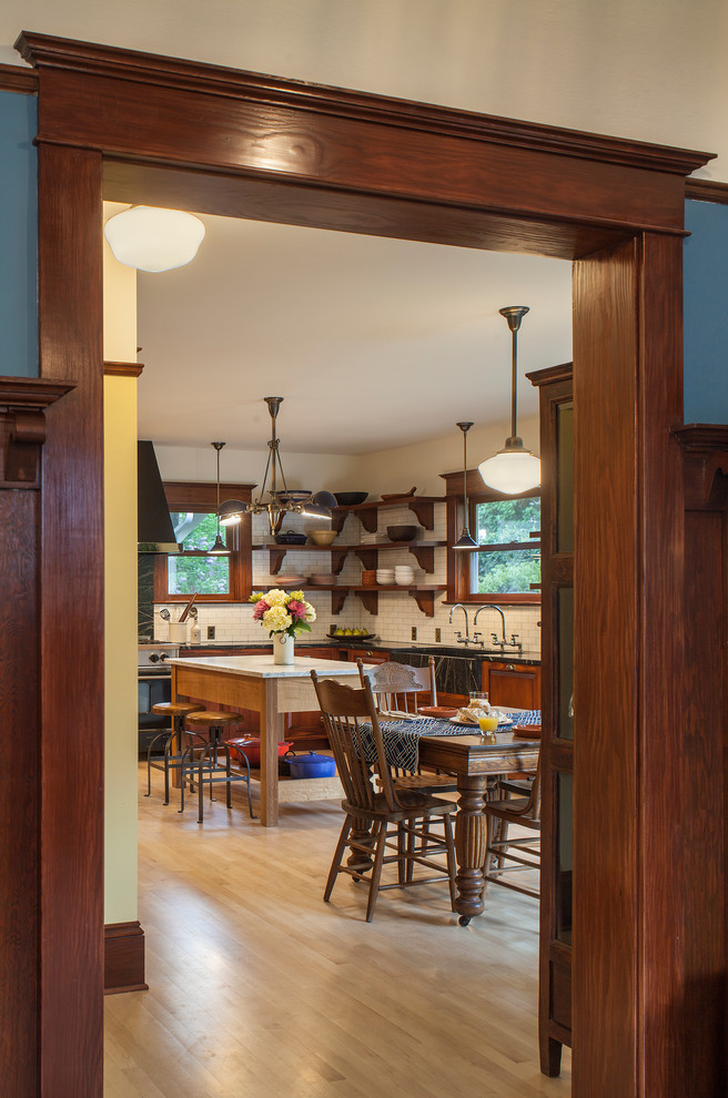 Inspiration for a huge craftsman l-shaped light wood floor eat-in kitchen remodel in Portland with an integrated sink, raised-panel cabinets, medium tone wood cabinets, soapstone countertops, white backsplash, subway tile backsplash, black appliances and an island