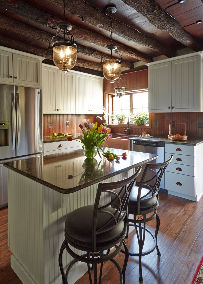 Mid-sized mountain style l-shaped medium tone wood floor and brown floor enclosed kitchen photo in Huntington with a farmhouse sink, glass-front cabinets, white cabinets, granite countertops, stainless steel appliances, an island, brown backsplash and wood backsplash