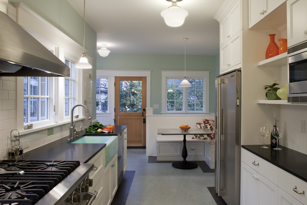 Inredning av ett amerikanskt mellanstort kök, med en rustik diskho, skåp i shakerstil, vita skåp, granitbänkskiva, vitt stänkskydd, stänkskydd i tunnelbanekakel, rostfria vitvaror och linoleumgolv