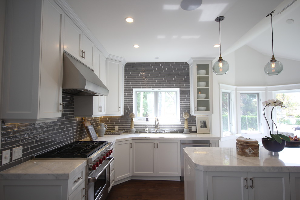 Large arts and crafts u-shaped dark wood floor eat-in kitchen photo in Los Angeles with a drop-in sink, shaker cabinets, white cabinets, marble countertops, gray backsplash, ceramic backsplash, stainless steel appliances and an island