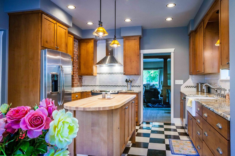 Mid-sized arts and crafts l-shaped linoleum floor eat-in kitchen photo in Seattle with a farmhouse sink, shaker cabinets, medium tone wood cabinets, granite countertops, white backsplash, ceramic backsplash, stainless steel appliances and an island