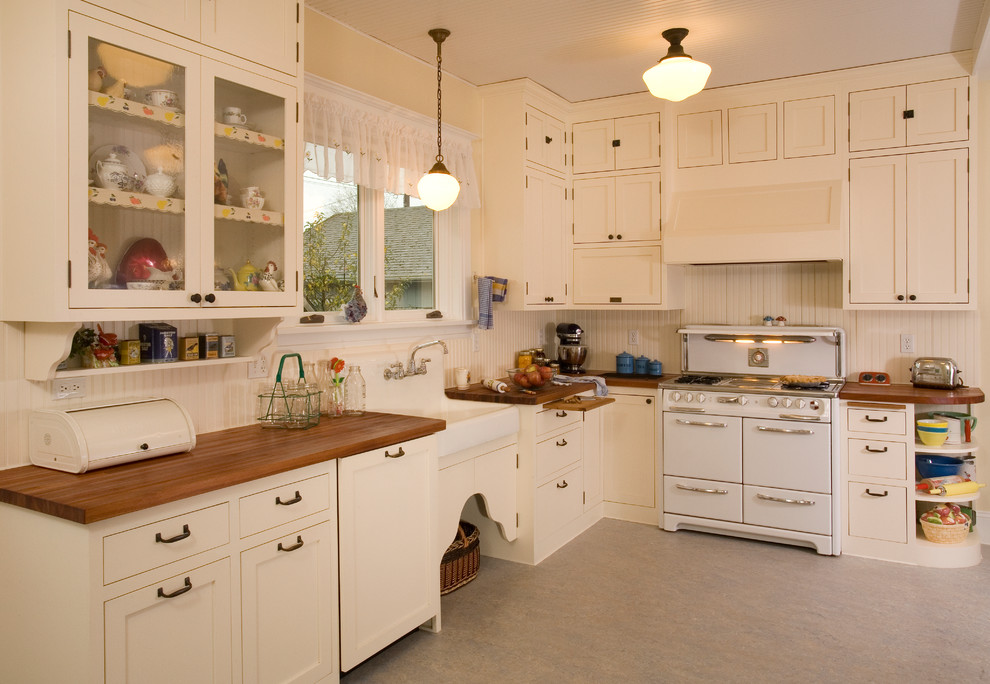 This is an example of a farmhouse kitchen in Seattle with a belfast sink, wood worktops, white cabinets, white appliances and shaker cabinets.