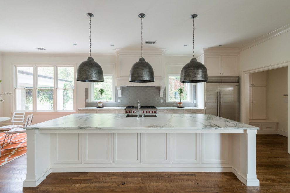 This is an example of a medium sized traditional single-wall enclosed kitchen in Atlanta with a submerged sink, recessed-panel cabinets, white cabinets, marble worktops, white splashback, metro tiled splashback, stainless steel appliances, dark hardwood flooring, an island and brown floors.