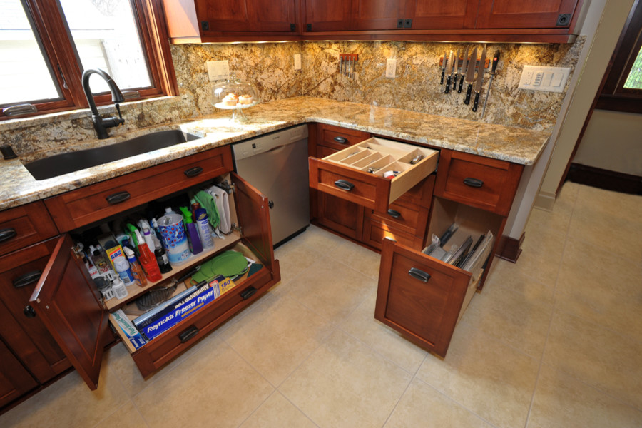 Klassisk inredning av ett kök, med en undermonterad diskho, luckor med infälld panel, skåp i mellenmörkt trä, granitbänkskiva, beige stänkskydd och integrerade vitvaror