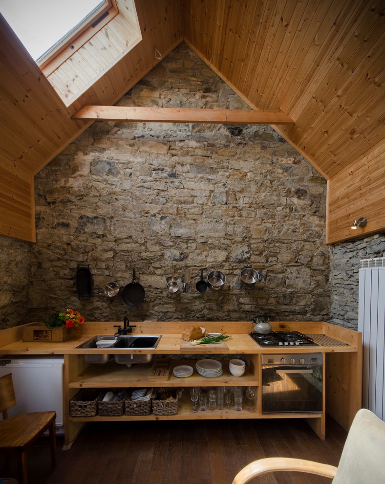 Diseño de cocina lineal rural sin isla con armarios abiertos, electrodomésticos blancos y pared de piedra