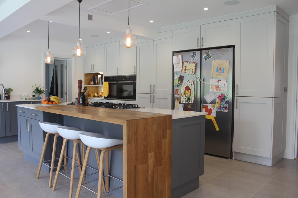 Moderne Wohnküche mit Schrankfronten im Shaker-Stil, weißen Schränken, Küchengeräten aus Edelstahl und Kücheninsel in Hertfordshire