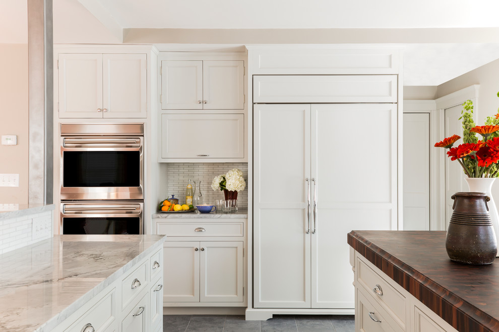 Elegant kitchen photo in Boston with recessed-panel cabinets, white cabinets, white backsplash, subway tile backsplash and paneled appliances