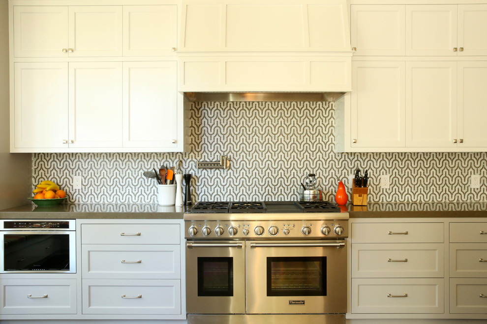 Immagine di una cucina design con ante con riquadro incassato, elettrodomestici in acciaio inossidabile e ante bianche