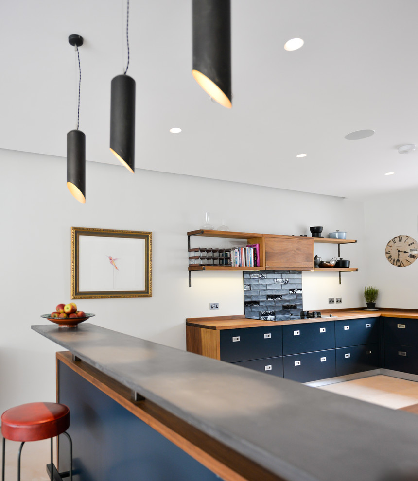 Idee per una cucina contemporanea di medie dimensioni con lavello da incasso, ante lisce, ante blu, top in legno, paraspruzzi nero, paraspruzzi con piastrelle in ceramica, elettrodomestici neri e pavimento in cemento