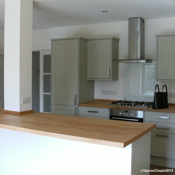 Example of a mid-sized trendy l-shaped bamboo floor eat-in kitchen design in Cambridgeshire with a farmhouse sink, gray cabinets, wood countertops, white backsplash, stainless steel appliances, an island and shaker cabinets