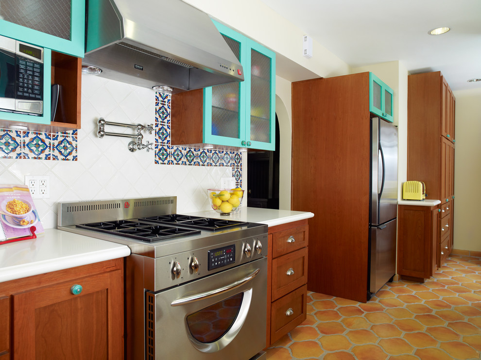 Example of a tuscan kitchen design in Los Angeles with stainless steel appliances, glass-front cabinets, blue cabinets, multicolored backsplash and quartz countertops