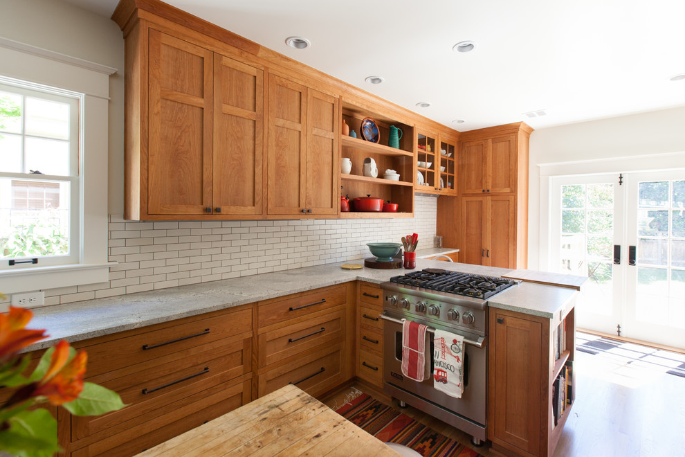 Bild på ett amerikanskt kök, med skåp i shakerstil, skåp i mellenmörkt trä, granitbänkskiva, vitt stänkskydd, stänkskydd i keramik, rostfria vitvaror, mellanmörkt trägolv, en köksö och brunt golv