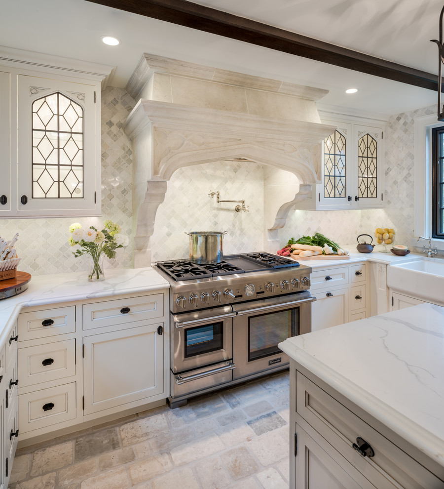 Traditional u-shaped kitchen/diner in Philadelphia with a belfast sink, white cabinets, marble worktops, white splashback, stone tiled splashback, stainless steel appliances, travertine flooring, an island and recessed-panel cabinets.