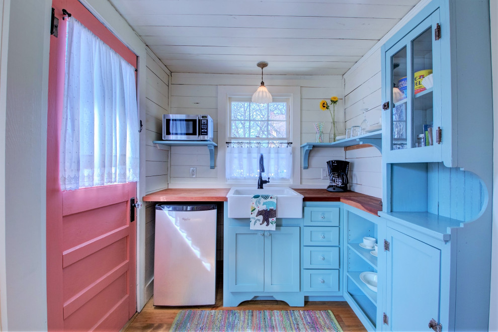 Photo of a small vintage l-shaped kitchen in Little Rock with a belfast sink, shaker cabinets, blue cabinets, wood worktops, white splashback, medium hardwood flooring, no island, brown floors, brown worktops, a timber clad ceiling, wood splashback and stainless steel appliances.