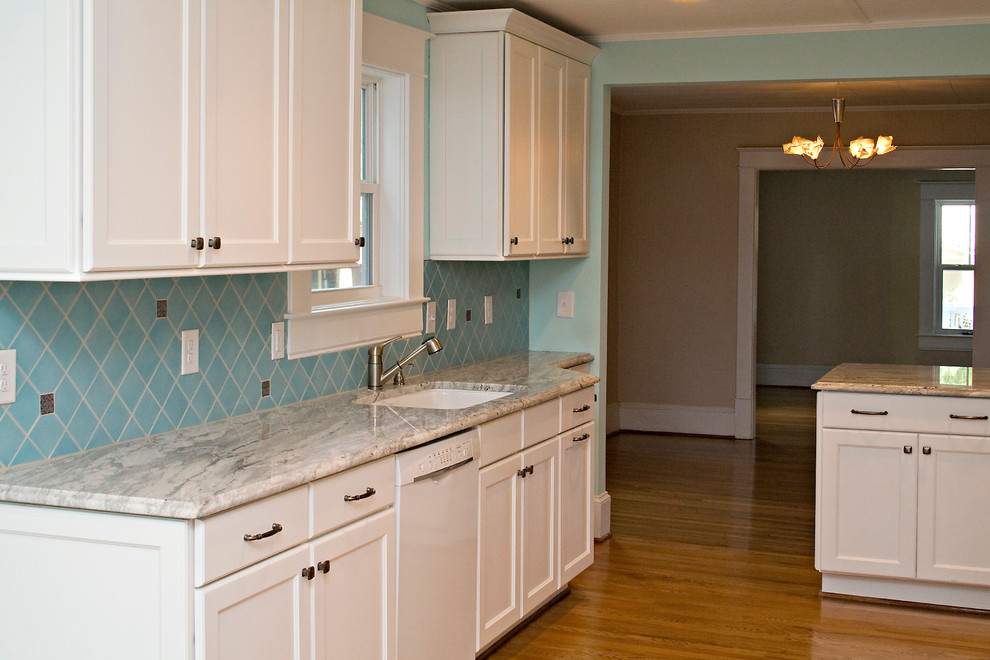 Foto på ett mellanstort funkis kök, med en undermonterad diskho, skåp i shakerstil, vita skåp, granitbänkskiva, blått stänkskydd, stänkskydd i keramik, vita vitvaror och ljust trägolv