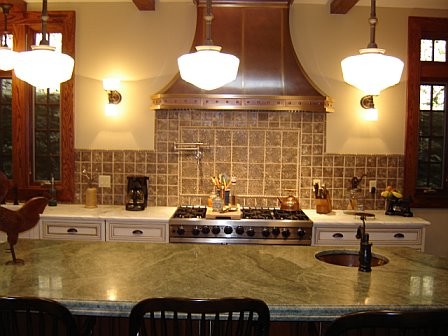 This is an example of a medium sized traditional u-shaped kitchen/diner in New York with a submerged sink, raised-panel cabinets, white cabinets, granite worktops, beige splashback, ceramic splashback, stainless steel appliances, brick flooring, an island and brown floors.