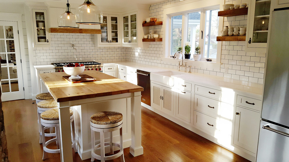 Inspiration för ett mellanstort lantligt kök, med en rustik diskho, skåp i shakerstil, vita skåp, marmorbänkskiva, vitt stänkskydd, stänkskydd i tunnelbanekakel, rostfria vitvaror, mellanmörkt trägolv och en köksö