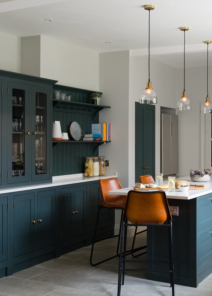 Inspiration pour une cuisine américaine parallèle traditionnelle avec un placard à porte shaker, des portes de placards vertess, une crédence verte, une crédence en bois, îlot, un sol gris et un plan de travail blanc.