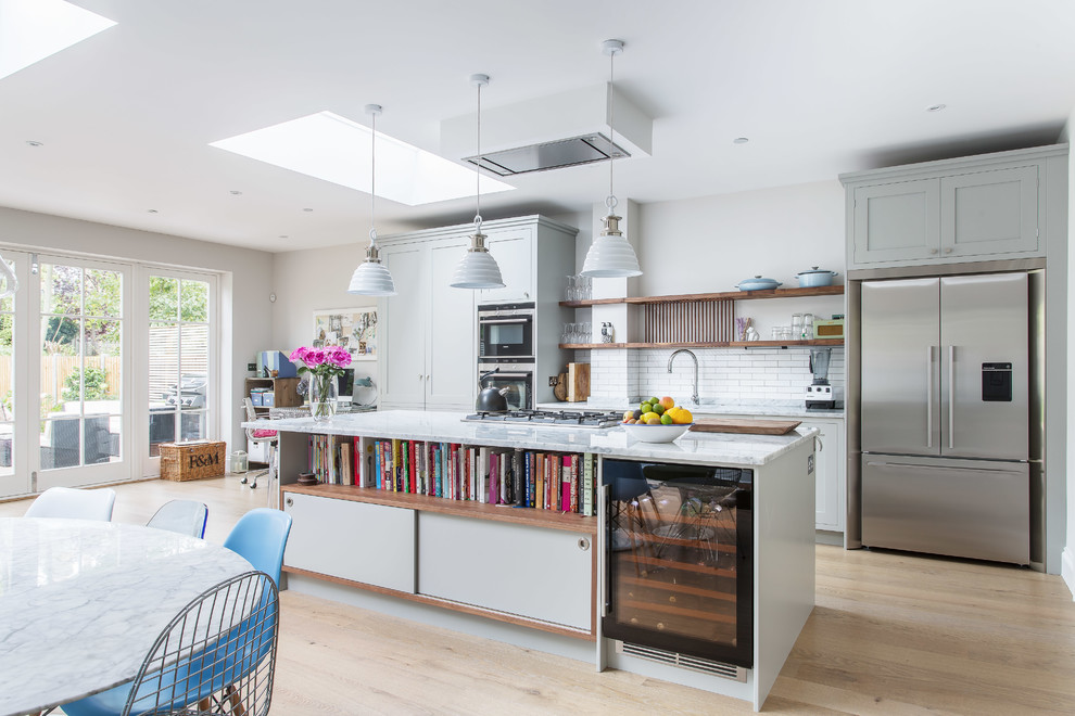 Trendy light wood floor eat-in kitchen photo in London with shaker cabinets, gray cabinets, marble countertops, white backsplash, stainless steel appliances, an island and subway tile backsplash