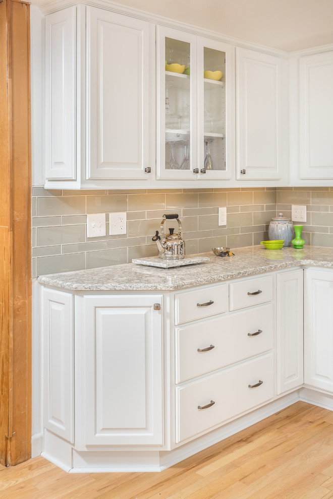 Inspiration for a small timeless u-shaped light wood floor and yellow floor eat-in kitchen remodel in Other with an undermount sink, raised-panel cabinets, white cabinets, quartz countertops, gray backsplash, glass tile backsplash and stainless steel appliances