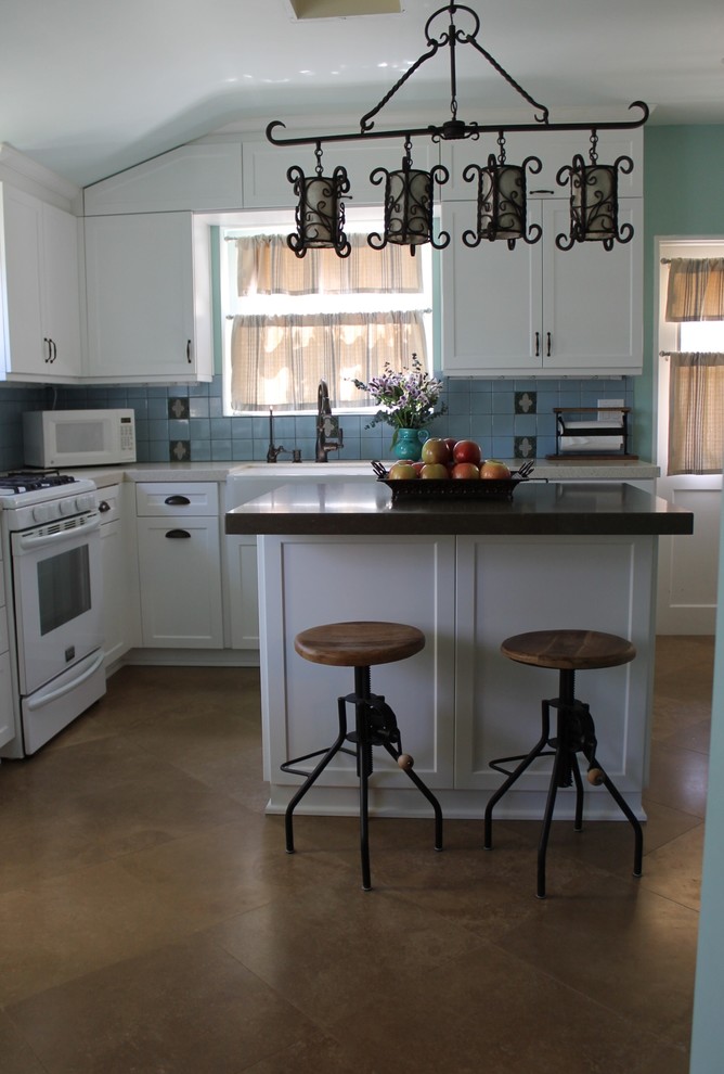 Bild på ett avskilt, mellanstort eklektiskt u-kök, med en rustik diskho, skåp i shakerstil, vita skåp, bänkskiva i kvarts, blått stänkskydd, stänkskydd i keramik, vita vitvaror, travertin golv och en köksö