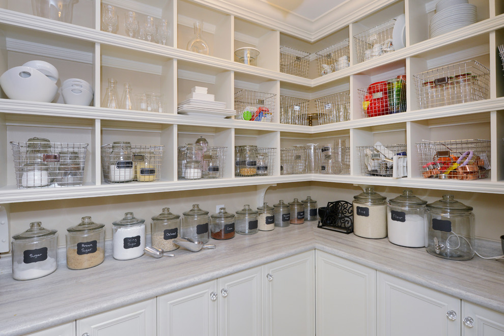 Cette photo montre une arrière-cuisine chic en L de taille moyenne avec un placard avec porte à panneau encastré, des portes de placard blanches, un plan de travail en stratifié et un sol en carrelage de porcelaine.