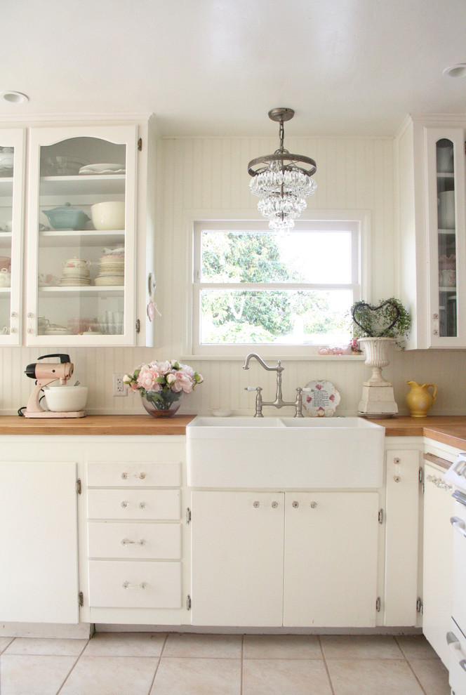 Shabby-Style Küche mit Landhausspüle, Glasfronten, weißen Schränken, Arbeitsplatte aus Holz und Küchenrückwand in Weiß in Santa Barbara